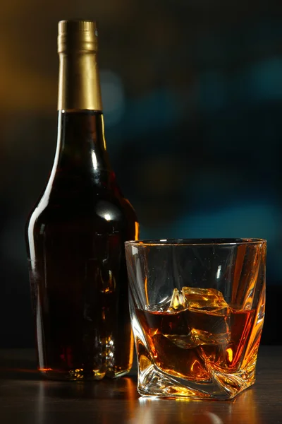 Стакан виски с бутылкой, на темном фоне — стоковое фото