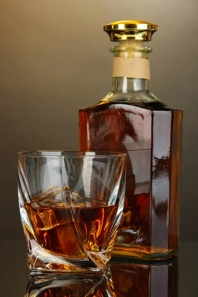 Glass of whiskey with bottle, on dark background — Stock Photo, Image