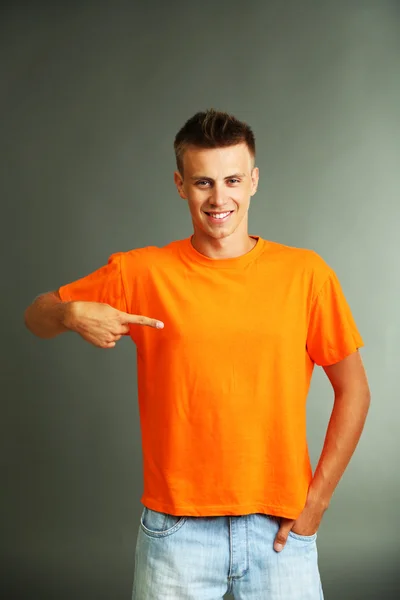 T-Shirt auf jungem Mann, auf grauem Hintergrund — Stockfoto