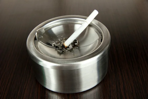 Posacenere e sigaretta in metallo su tavolo di legno — Foto Stock