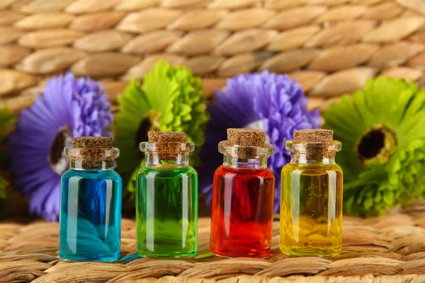 Пляшки з кольоровими рідинами на плетеному дерев'яному фоні — стокове фото