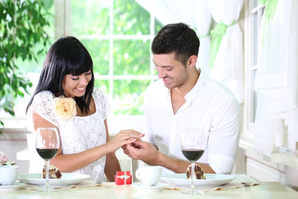 Man proposing and holding up an engagement ring his woman over restaurant table — Stock Photo, Image