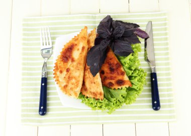 renkli ahşap zemin üzerinde plaka üzerinde taze otlar ile lezzetli chebureks