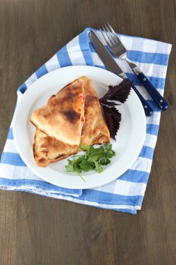 Pizza calzones tabakta üzerine peçete ahşap masa üzerinde