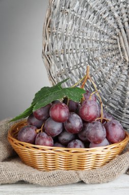 hasır sepet tabloda gri arka plan üzerinde olgunlaşmış lezzetli üzüm