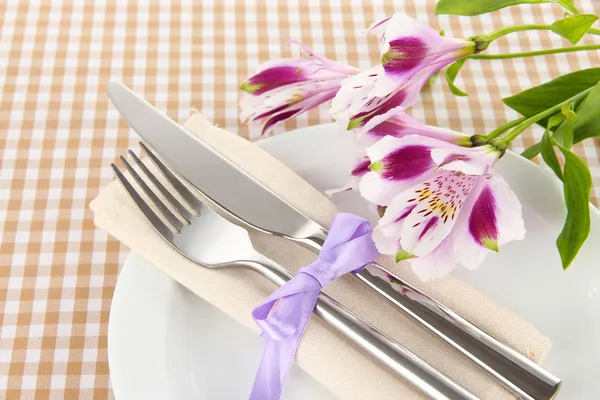 Mesa de comedor festiva con flores sobre fondo a cuadros — Foto de Stock