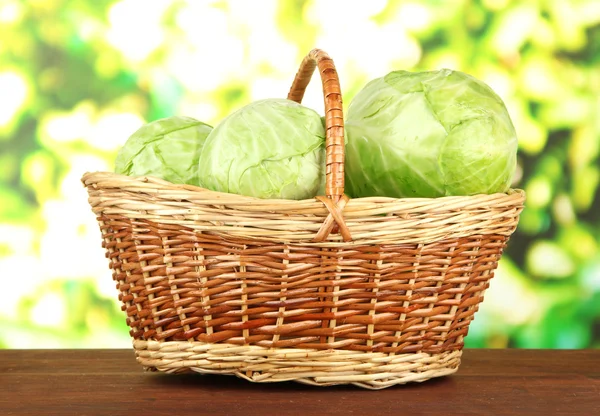 Green cabbage in wicker basket, on bright background — Stock Photo, Image