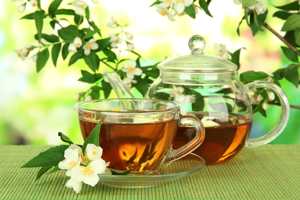 Cup of tea with jasmine, on bamboo mat, on bright background — Stock Photo, Image