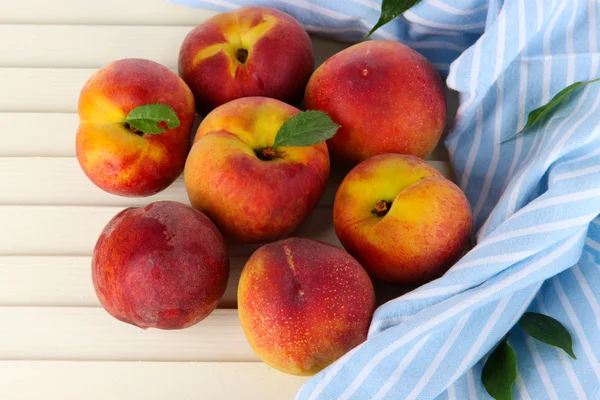 Peaches on napkin on wooden table — Stock Photo, Image