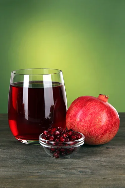 Glass of fresh garnet juice on table on green background — Stock Photo, Image