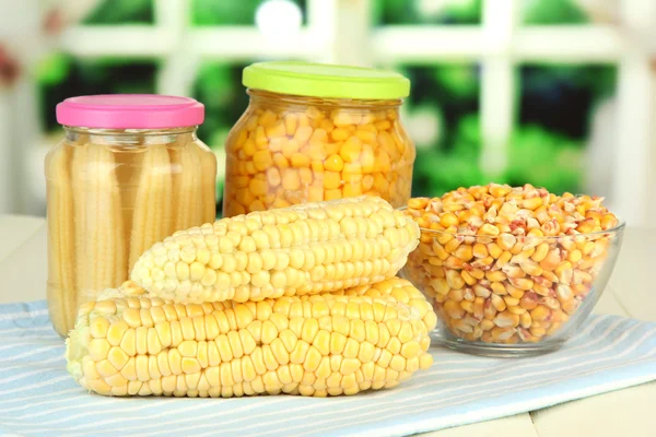 Fresh, canned and dried corn on wooden table, on bright background — Stock Photo, Image