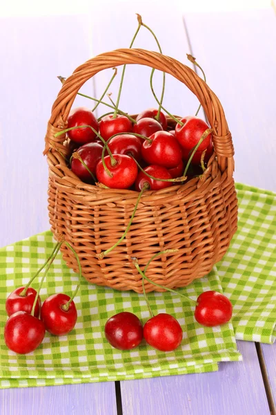 Cherry berries in wicker basket on wooden table close up — Stock Photo, Image