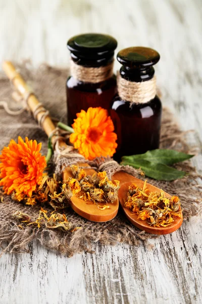 Geneeskundeflessen en calendula bloemen op houten achtergrond — Stockfoto