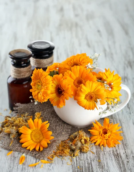 Medicine bottles and calendula flowers on wooden background — Stock Photo, Image