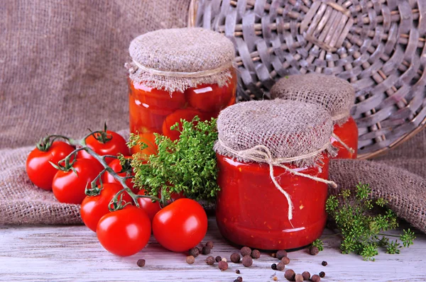 Tasty canned and fresh tomatoes on wooden table — Stock Photo, Image