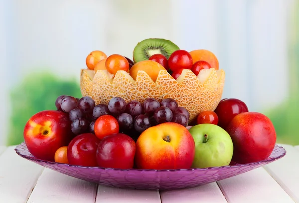 Surtido de frutas jugosas sobre mesa de madera, sobre fondo brillante — Foto de Stock
