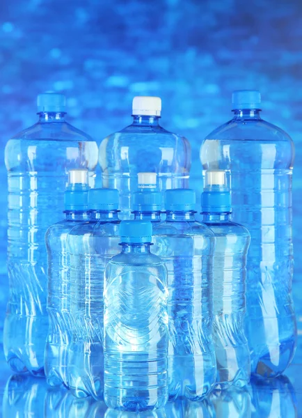 Acqua in diverse bottiglie su sfondo blu — Foto Stock