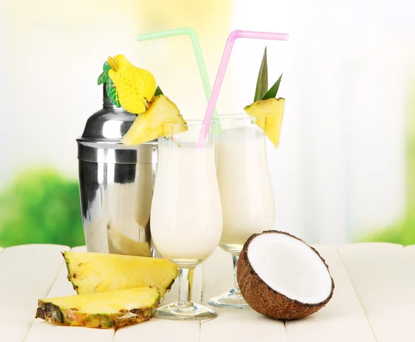 Pina colada drankje in cocktail glazen en metalen shaker, op lichte achtergrond — Stockfoto
