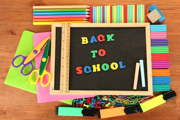 Small chalkboard with school supplies on wooden background. Back to School — Stock Photo, Image