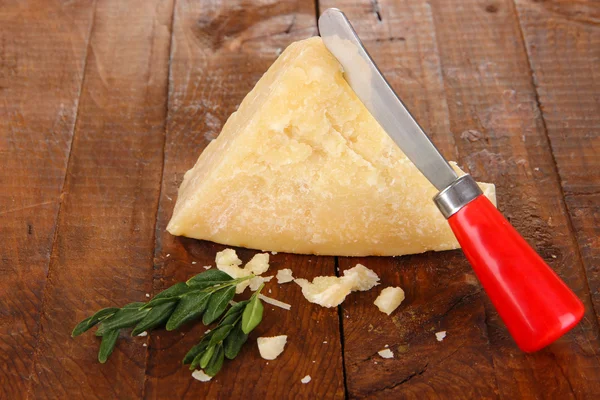 Piece of Parmesan cheese with knife on wooden table close-up — Stock Photo, Image