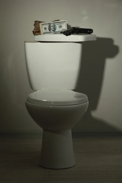 Money and gun on toilet tank in a bathroom — Stock Photo, Image