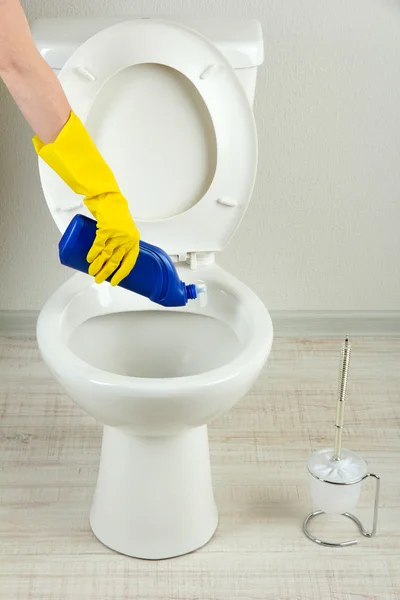 Woman hand with spray bottle cleaning a toilet bowl in a bathroom — Stock Photo, Image