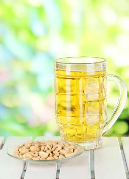 Beer in glass and nuts on table on nature background — Stock Photo, Image