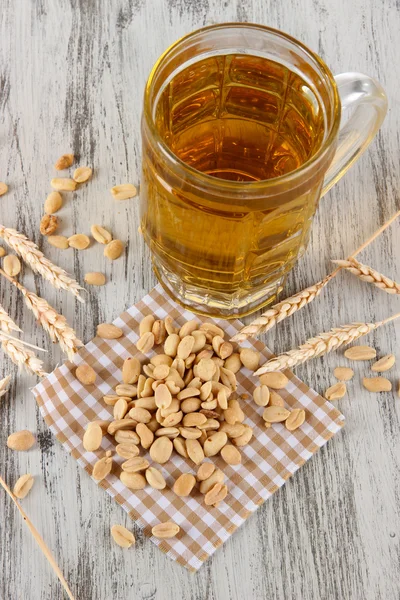 Pivo ve sklenici a ořechy na ubrousek na dřevěný stůl — Stock fotografie