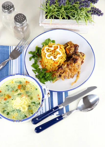 La sopa y el arroz con la carne en los platos a la servilleta a la mesa — Foto de Stock