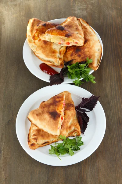 Pizzaschalen auf Tellern auf Holztisch — Stockfoto