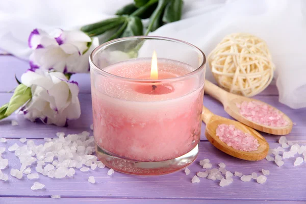 Beautiful pink candle with flowers on purple wooden background — Stock Photo, Image