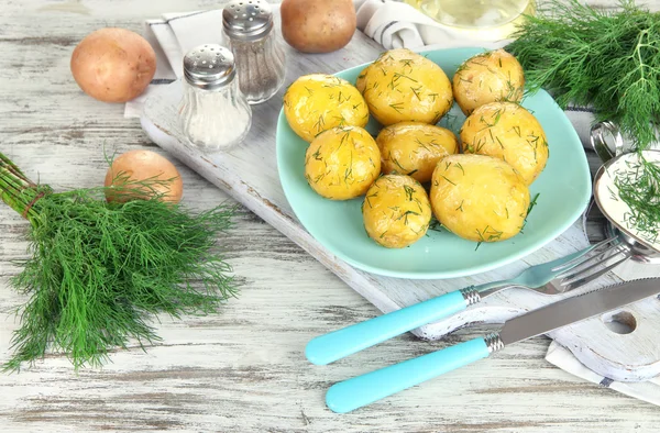 Boiled potatoes on platen on wooden board near napkin on wooden table — Stock Photo, Image