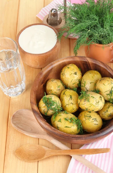 Boiled potatoes on wooden bowl near napkin on wooden table — Stock Photo, Image