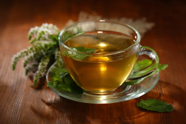 Xícara de chá de ervas com flores frescas de hortelã na mesa de madeira — Fotografia de Stock