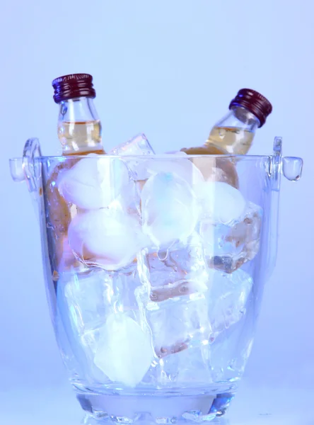 Minibar bottles in bucket with ice cubes, on color background — Stock Photo, Image