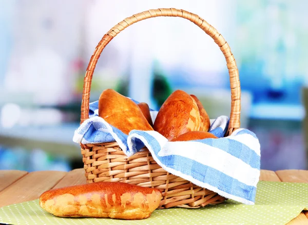 Fresh baked pasties in wicker basket, on bright background — Stock Photo, Image