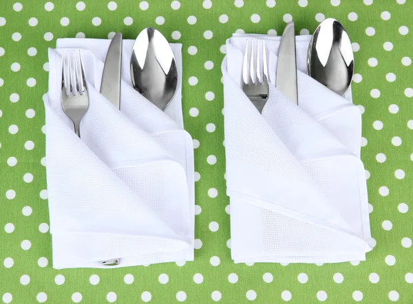 Folded napkin with fork, spoon and knife on color background — Stock Photo, Image