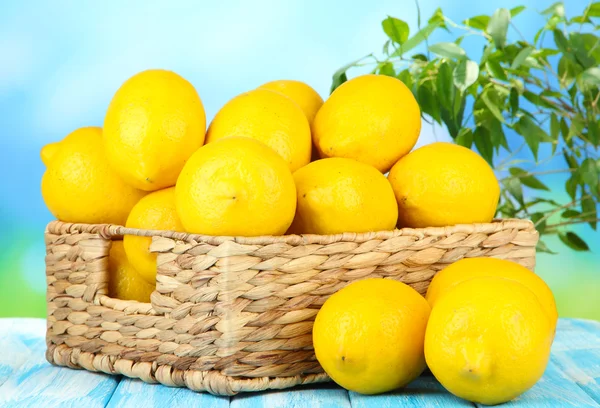 Limones maduros en canasta de mimbre sobre mesa sobre fondo brillante —  Fotos de Stock