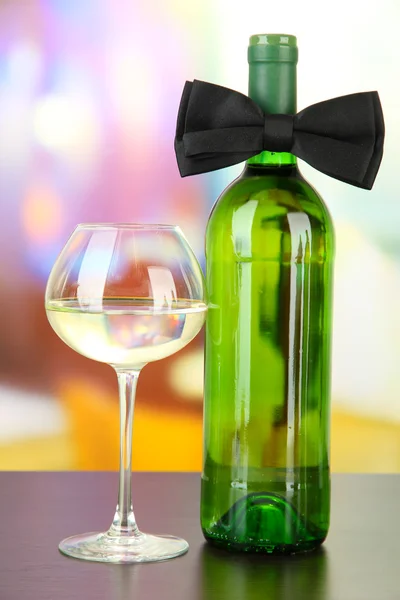 Black bow tie on wine bottle on bright background — Stock Photo, Image