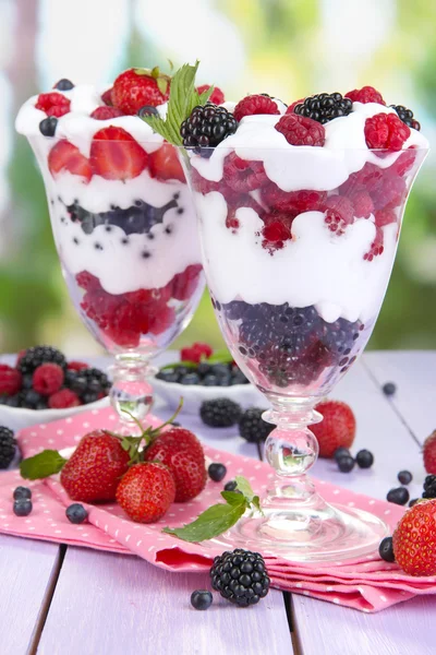 Natural yogurt with fresh berries on wooden table on green background — Stock Photo, Image