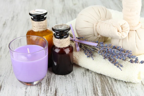 Stilleben med lavendel ljus, tvål, massage bollar, flaskor, tvål och färsk lavendel, på trä bakgrund — Stockfoto