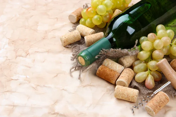 Бутылка вина, винограда и пробок на старом бумажном фоне — стоковое фото