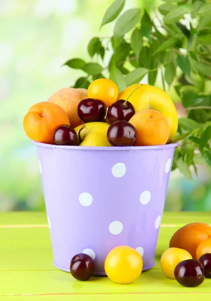 Frutas de verão brilhantes em balde na mesa de madeira no fundo natural — Fotografia de Stock
