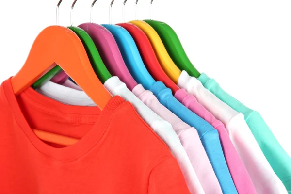 Different shirts on colorful hangers on white background — Stock Photo, Image