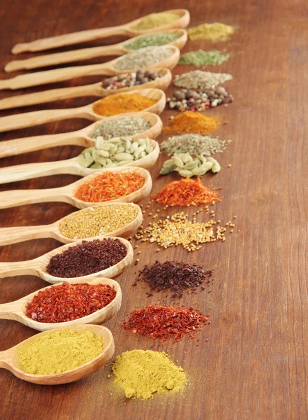 Assortment of spices in wooden spoons on wooden background — Stock Photo, Image