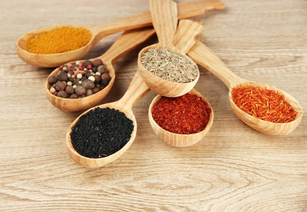 Assortment of spices in wooden spoons on wooden background — Stock Photo, Image