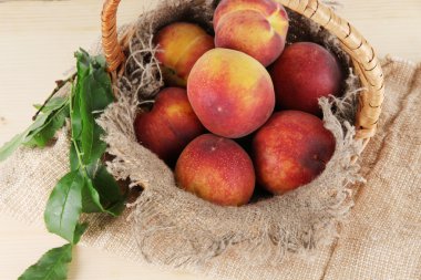 Şeftali sepeti ahşap masa üstünde çul üzerinde