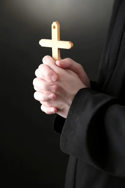 Sacerdote segurando cruz, no fundo preto — Fotografia de Stock