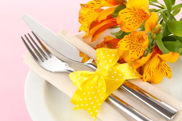 Nastavení slavnostní jídelní stůl s květinami na růžovém pozadí — Stock fotografie