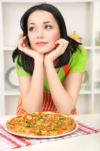 Tjej hemmafru med läckra pizza på kök bakgrund — Stockfoto